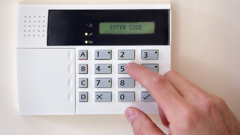 A woman using burglar alarms system panel